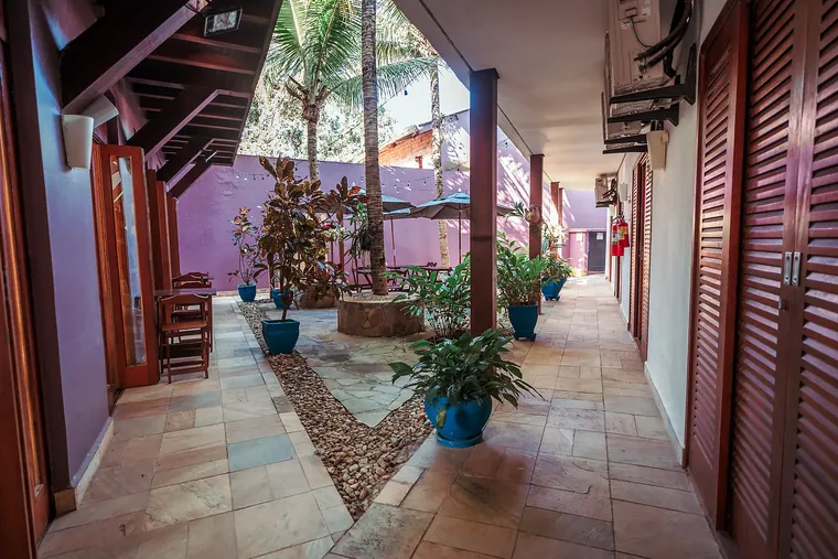 Corredor da Pousada Brigitte com plantas e paredes lilás
