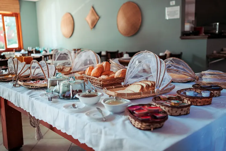 Buffet do café da manhã com pães, bolos e frios na sala verde-água