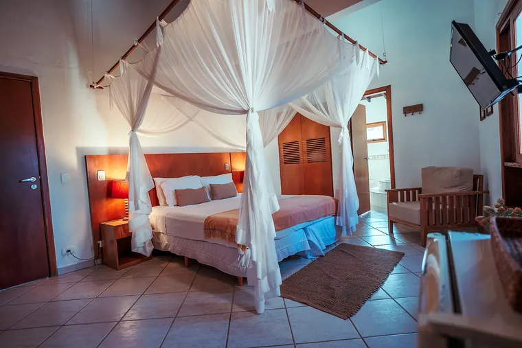 Suíte Deluxe da Pousada Brigitte com cama de casal e mosquiteiro branco