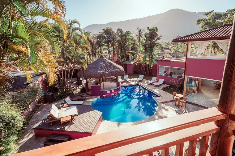 Vista aérea da piscina da Vila Bardot com o gazebo de sapê e a serra ao fundo