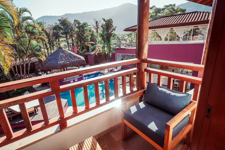 Varanda com sofá voltada para a piscina da Vila Bardot