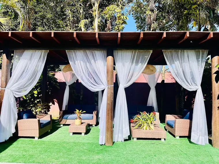 Lounge com cortinas brancas, sofás e mesas na Vila Bardot