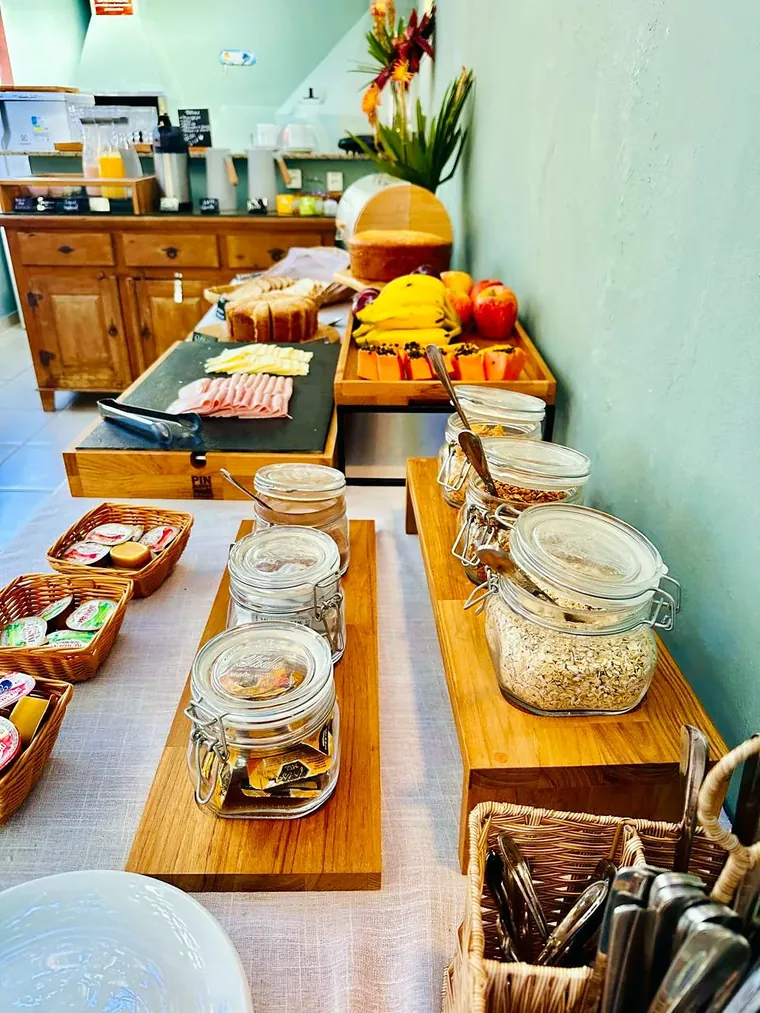 Mesa do café com frutas, frios, granola e pães