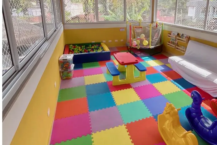 Sala das crianças da Vila Bardot com piscina de bolinhas, cama elástica, tatame colorido e estante de livros