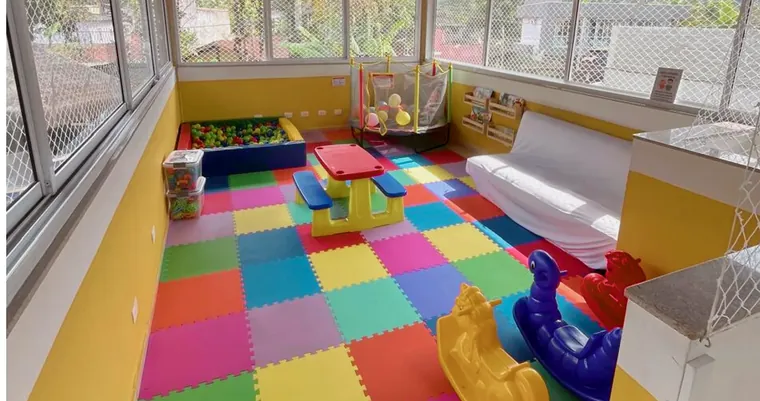Sala das crianças da Vila Bardot vista por inteiro, com sofá e estante de livros